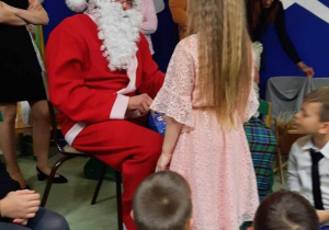 Święty Mikołaj wręcza dziewczynce prezent