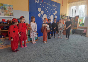 Grupa dzieci w przebraniach podczas występu dla emerytowanych nauczycieli i pracowników przedszkola.