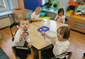 Dzieci przy stoliku wykonują kotyliony.
