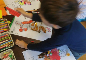 Dzieci przy stolikach projektują stroje dla postaci z "Królewny Śnieżki" z różnych materiałów plastycznych.