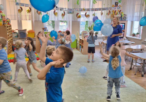 Dzieci odbijają balony w kolorze niebieskim.
