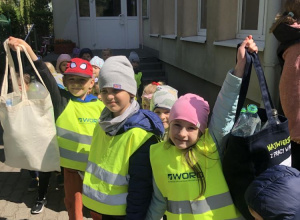 Dzieci trzymające ekologiczne torby wypełnione plastikowymi butelkami.