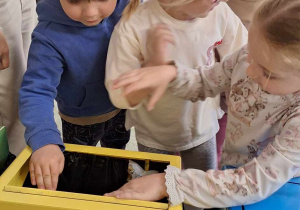 Dzieci wrzucają śmieci do odpowiedniego pojemnika do recyklingu.