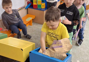 Chłopiec wrzuca śmieci do odpowiedniego pojemnika do recyklingu.
