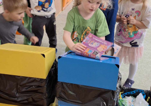 Chłopiec wrzuca śmieci do odpowiedniego pojemnika do recyklingu.