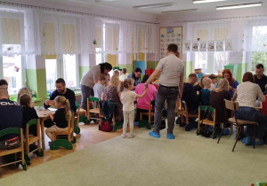 Rodzice i dzieci wykonują dekoracje wielkanocne.