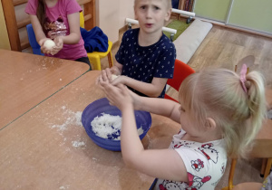 Dzieci siedzą przy stoliku i wykonują kule do kąpieli