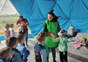 Chłopcy i dziewczynki stoją w dwóch kolejkach do założenia gogli VR.