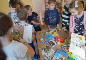 Dzieci oglądają książki w bibliotece przedszkolnej.